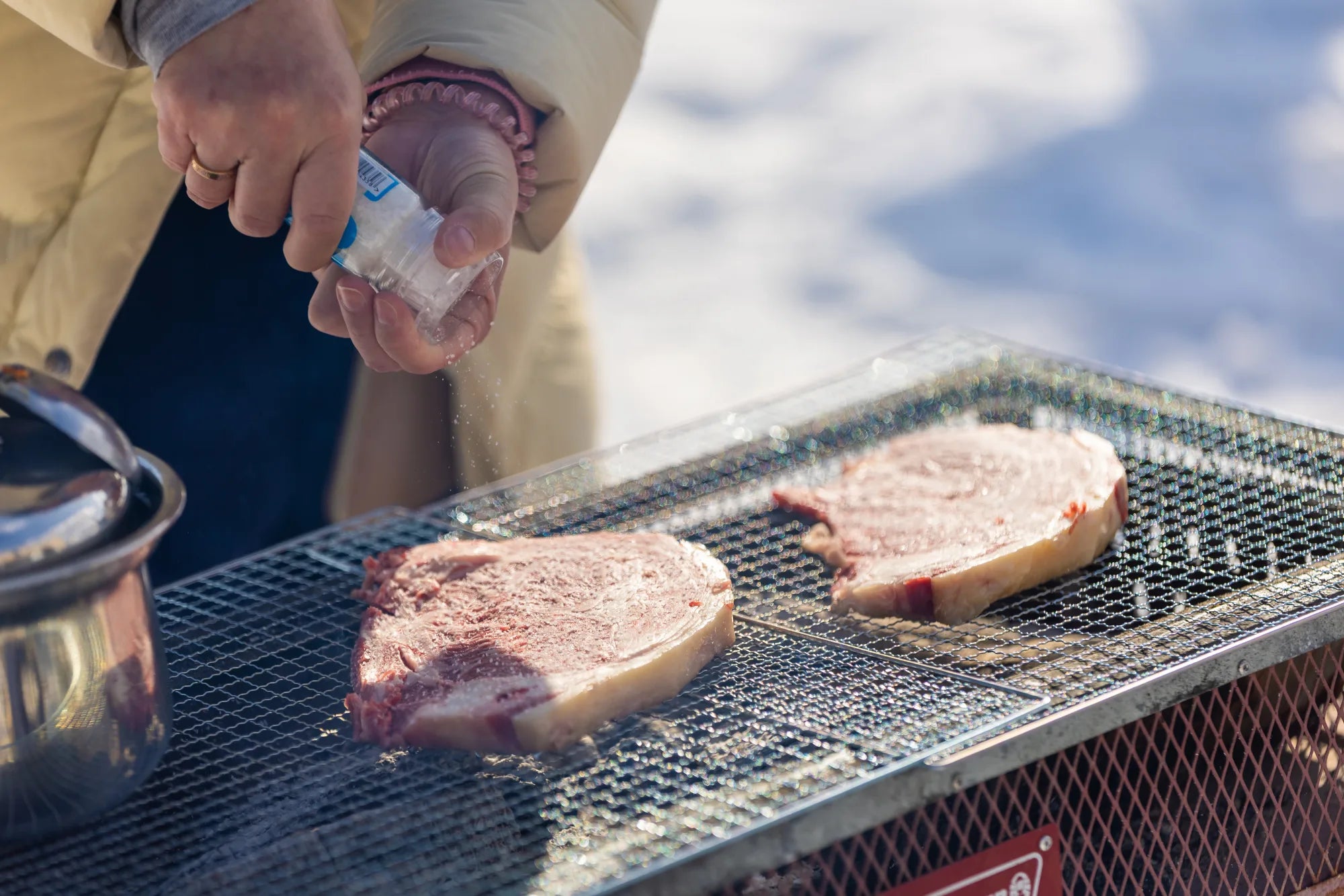 Ellie seasoning ribeyes with kosher salt before the grill